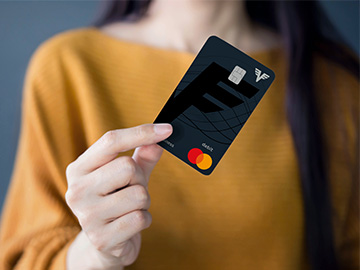 Eine junge Frau hält eine schwarze Karte in die Kamera