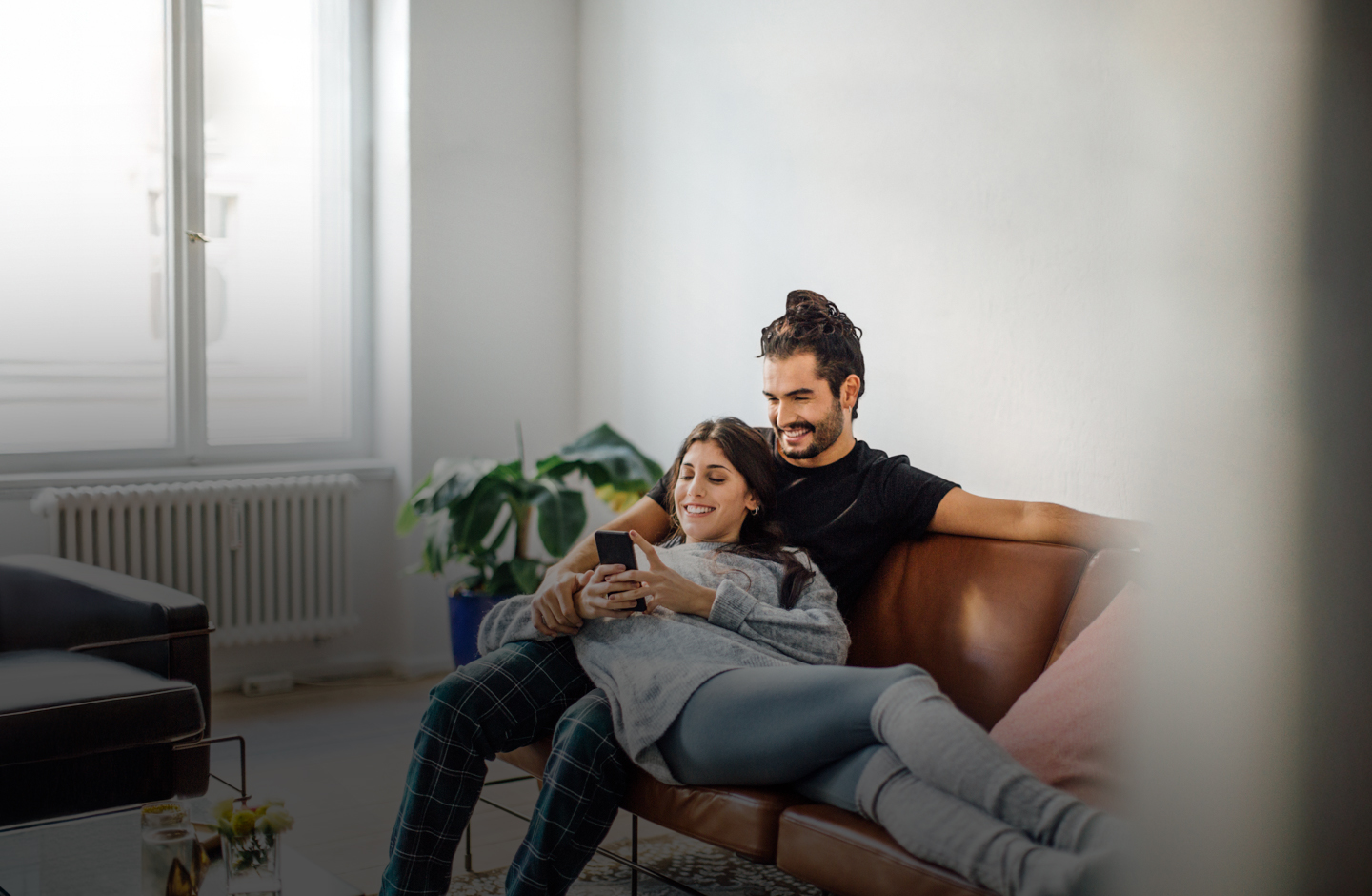 An Mann und eine Frau liegen auf der Couch und schauen aufs Handy